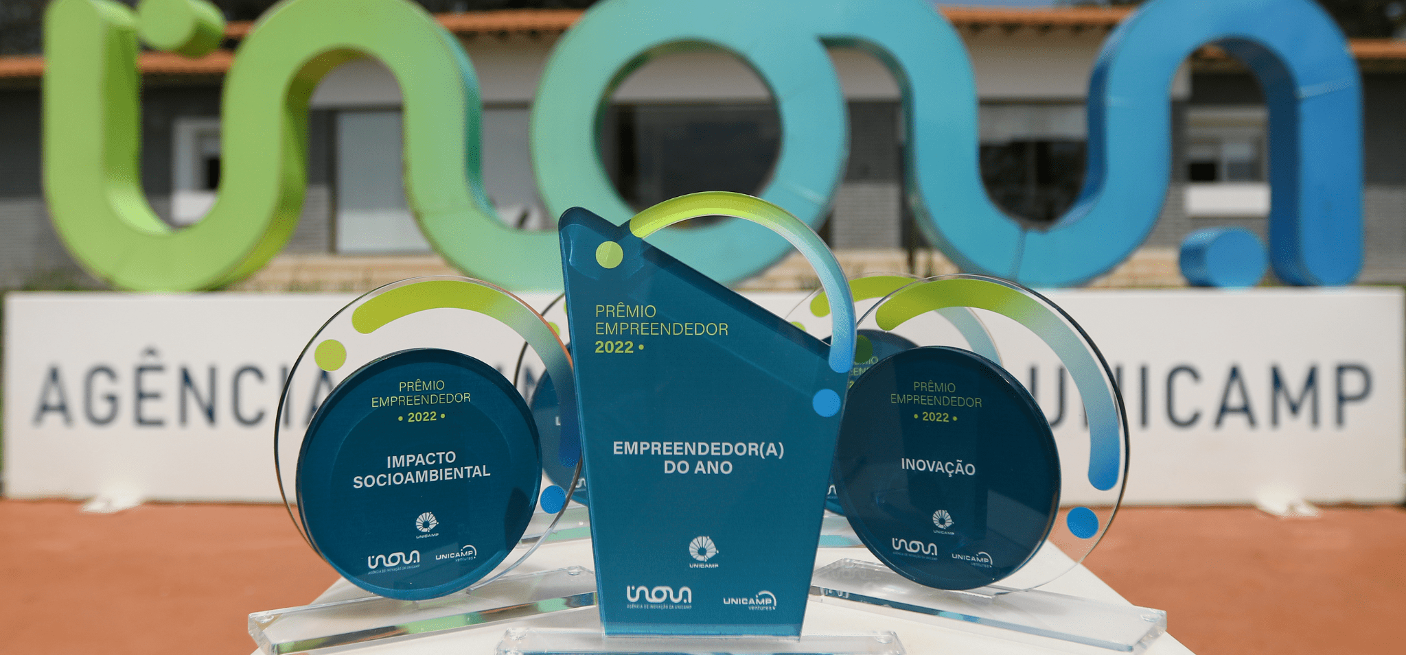 A imagem mostra os troféus do Prêmio Empreendedor 2023 da Unicamp. Fim da descrição.